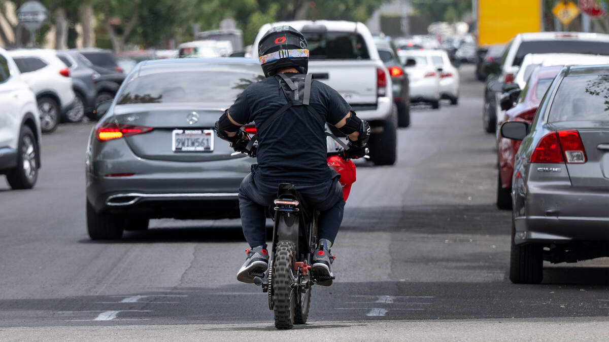 A cyclist on an electric motorcycle travels along 15th Street in downtown Modesto, July 2, 2026.